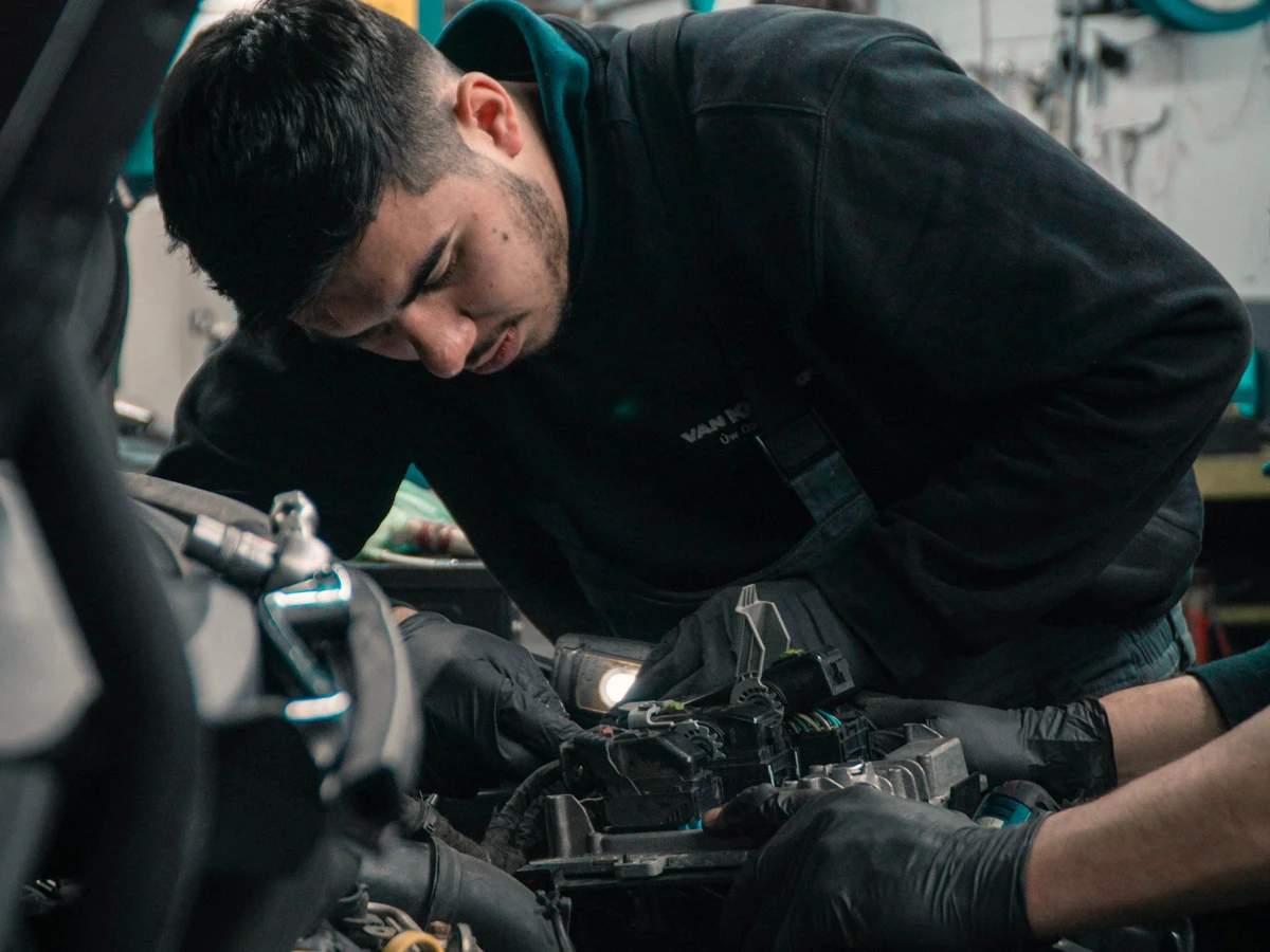 Kfz-Mechatroniker arbeitet im Motorraum eines Autos