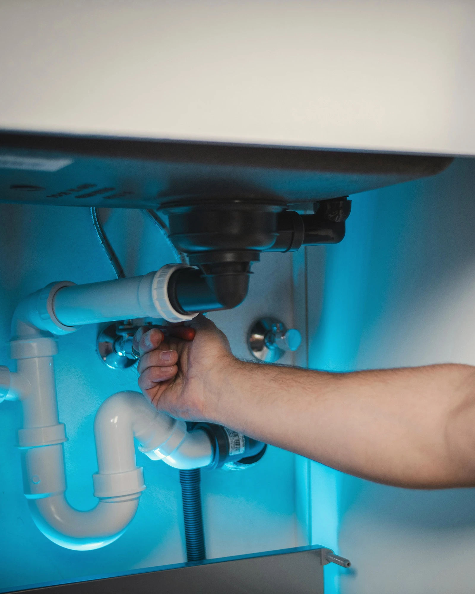 Anlagenmechaniker montiert den Siphon unter einem Waschbecken