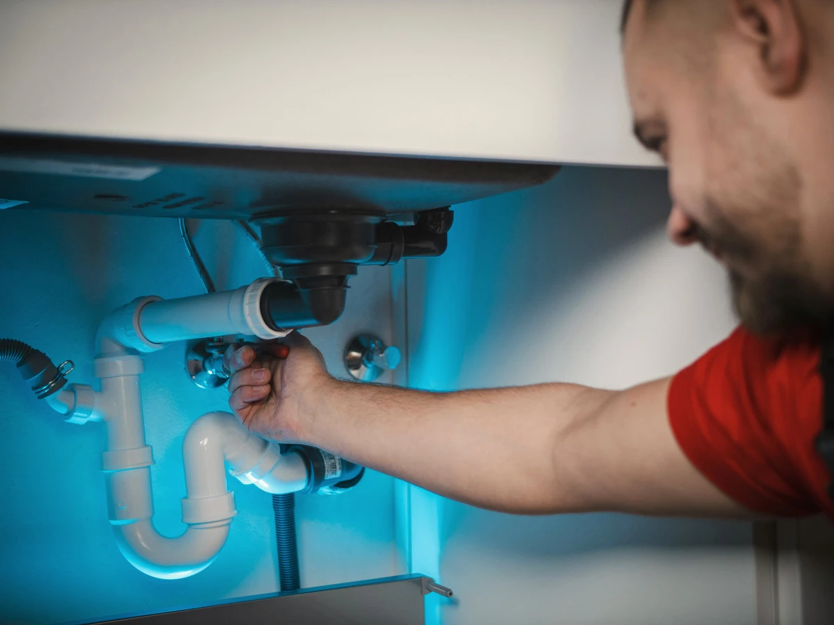 Anlagenmechaniker montiert einen Siphon unter dem Waschbecken